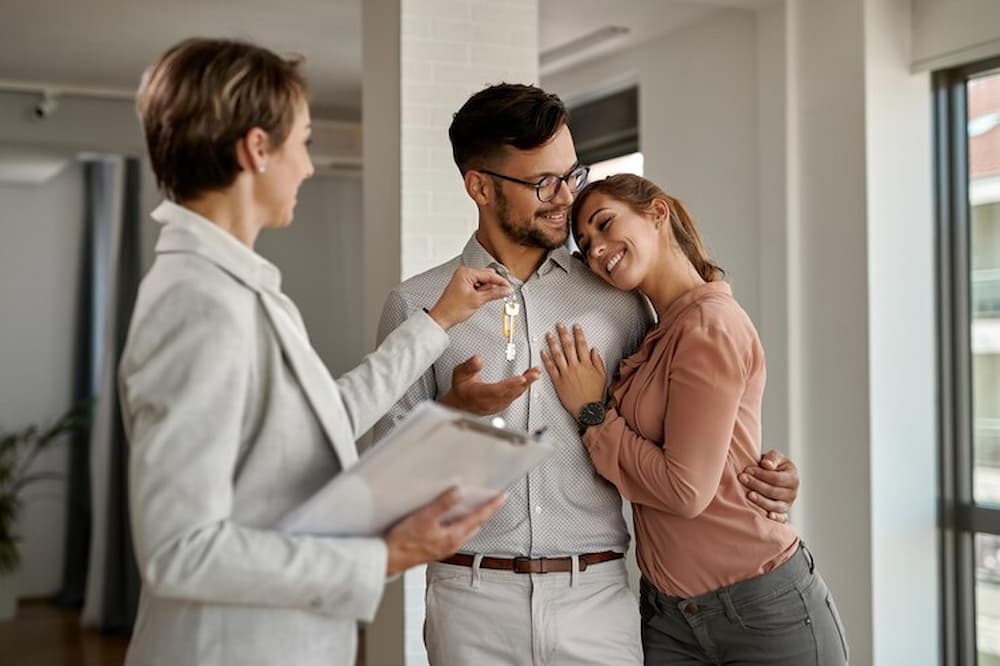 Pareja recibiendo llaves de agente inmobiliario